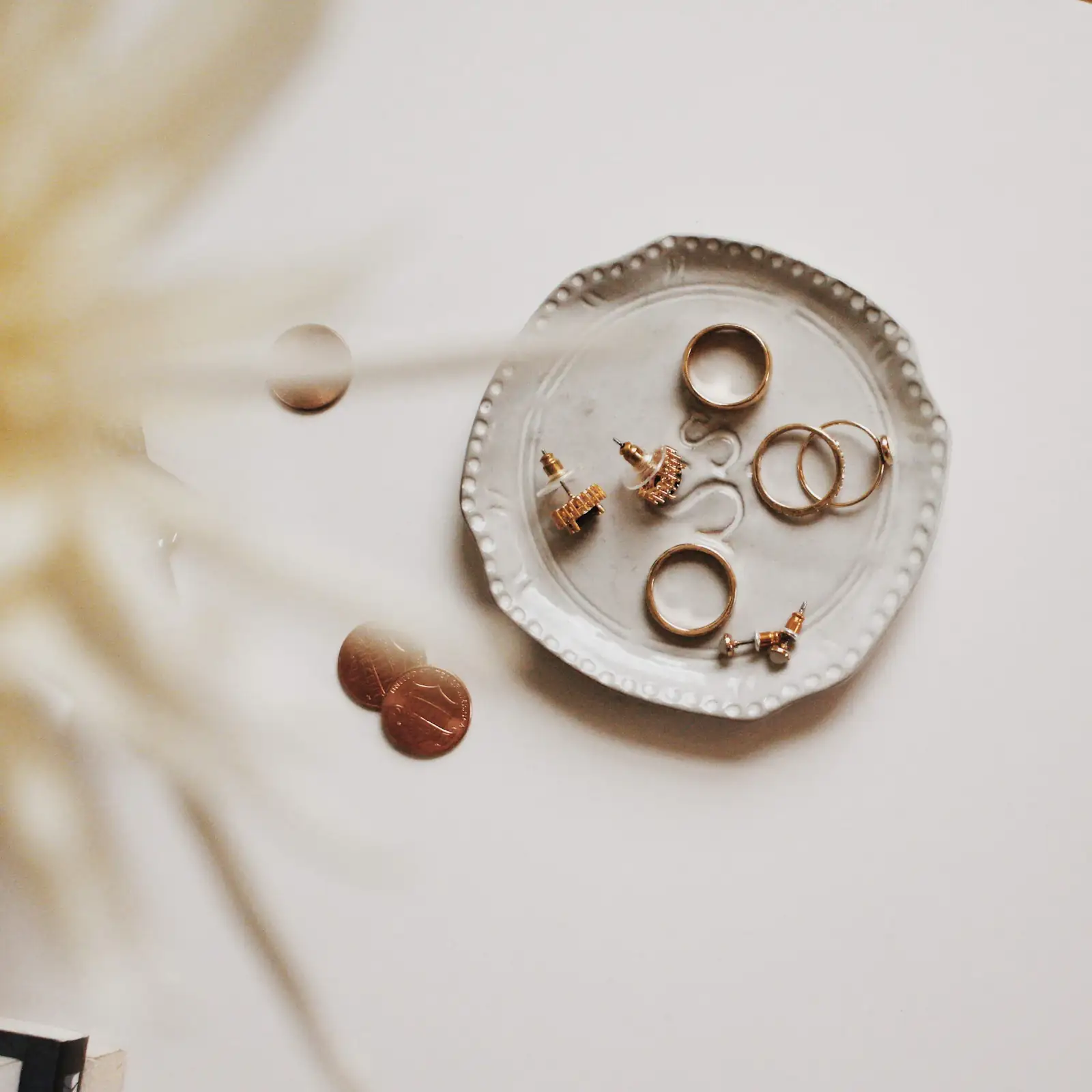 Gold rings and earrings in a small cream ceramic dish